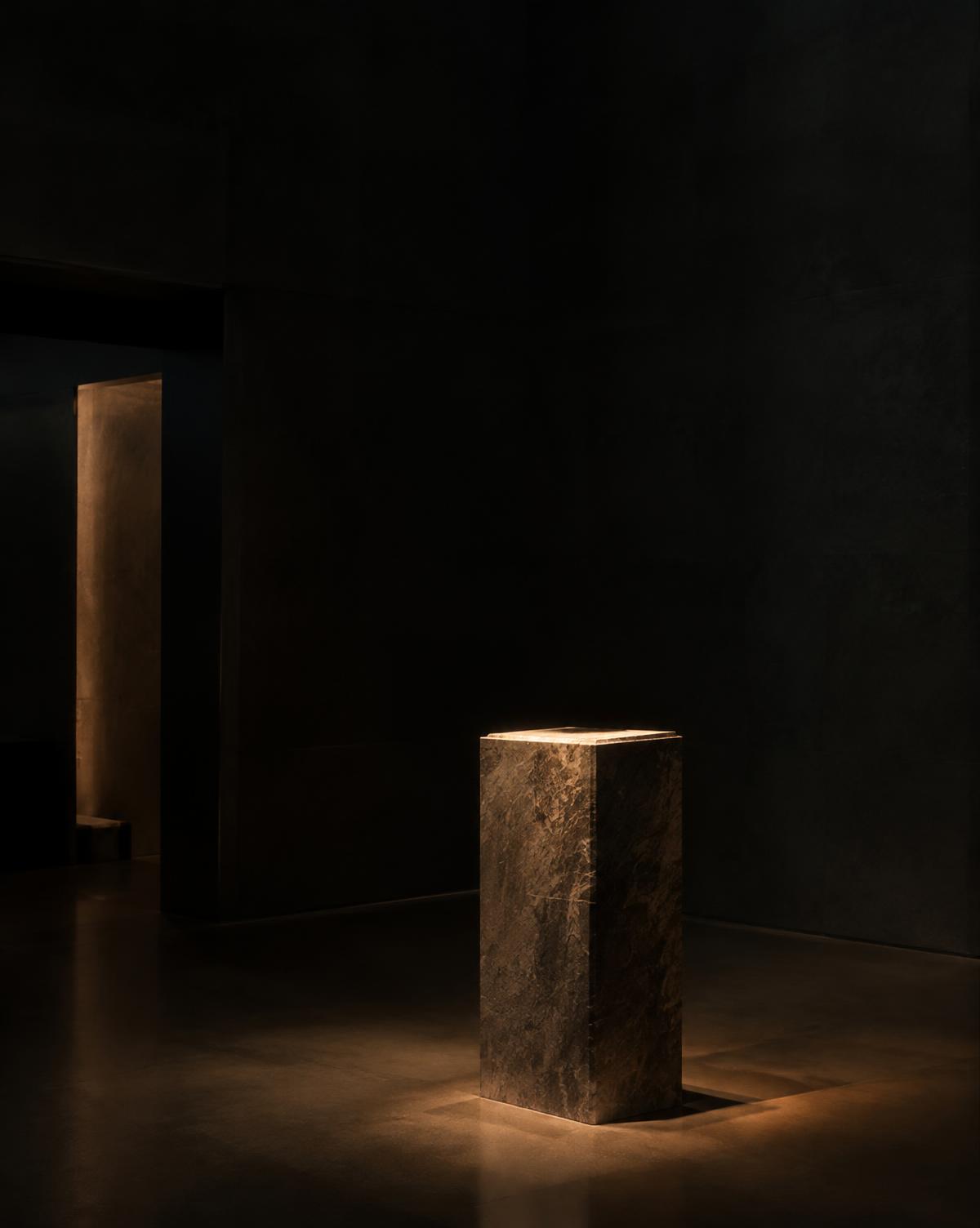 Stone plinth lit by a narrow beam of warm light